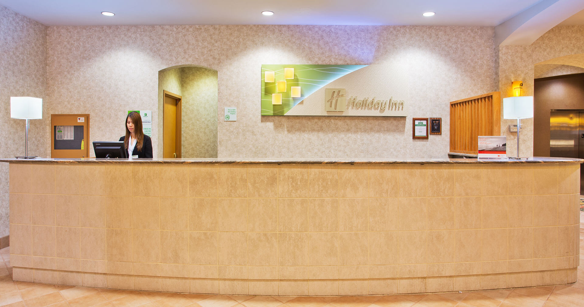 An employee working at the check-in counter at the Holiday Inn North Vancouver