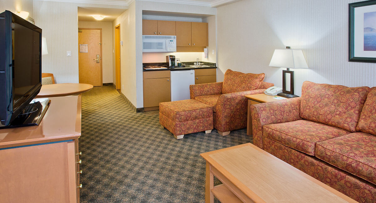 A sitting room with sofas, a table and kitchenette at the Holiday Inn North Vancouver