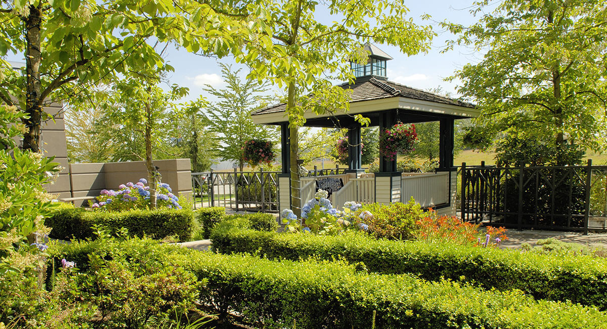 Gazebo surrounded by flowers and trees in the sunshine at Holiday Inn North Vancouver