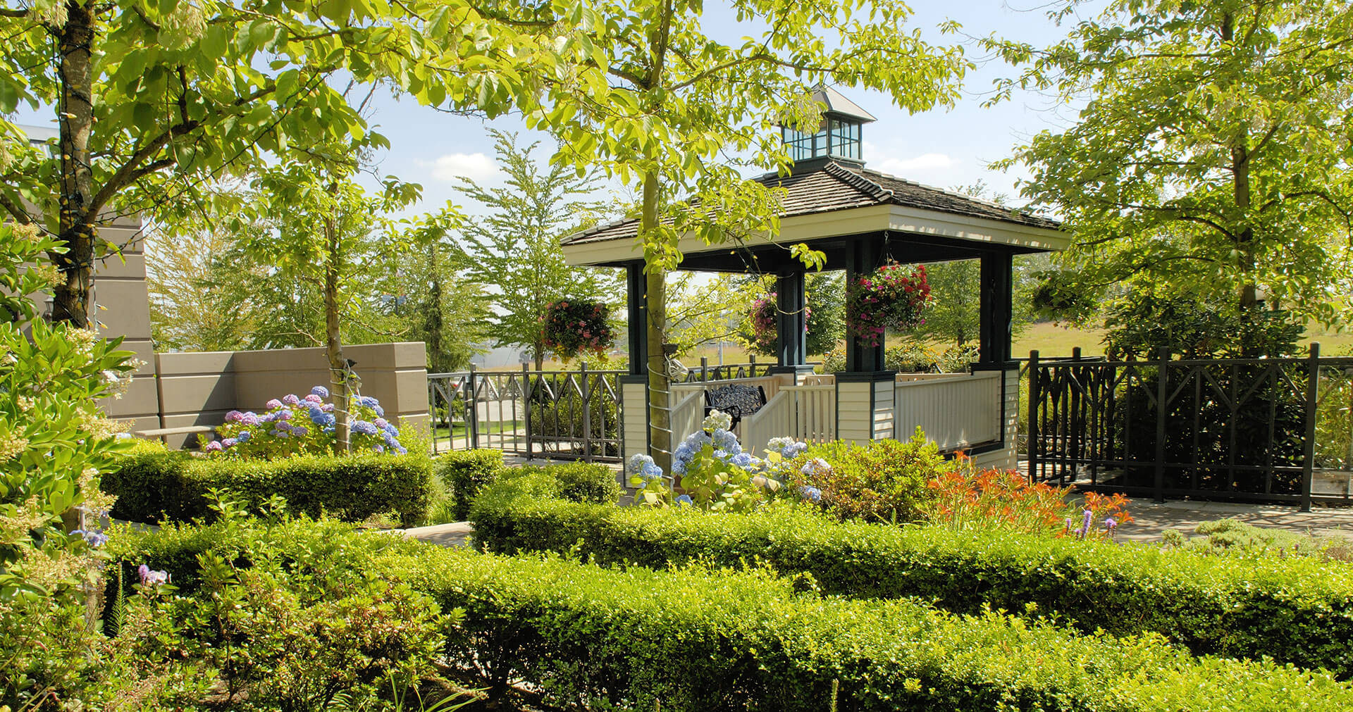 Gazebo nestled among flowers, manicured trees and shrubs